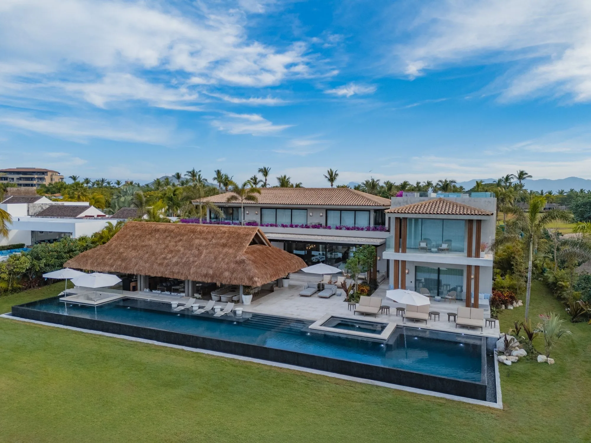 Vista aérea de una villa con palapa y alberca infinita